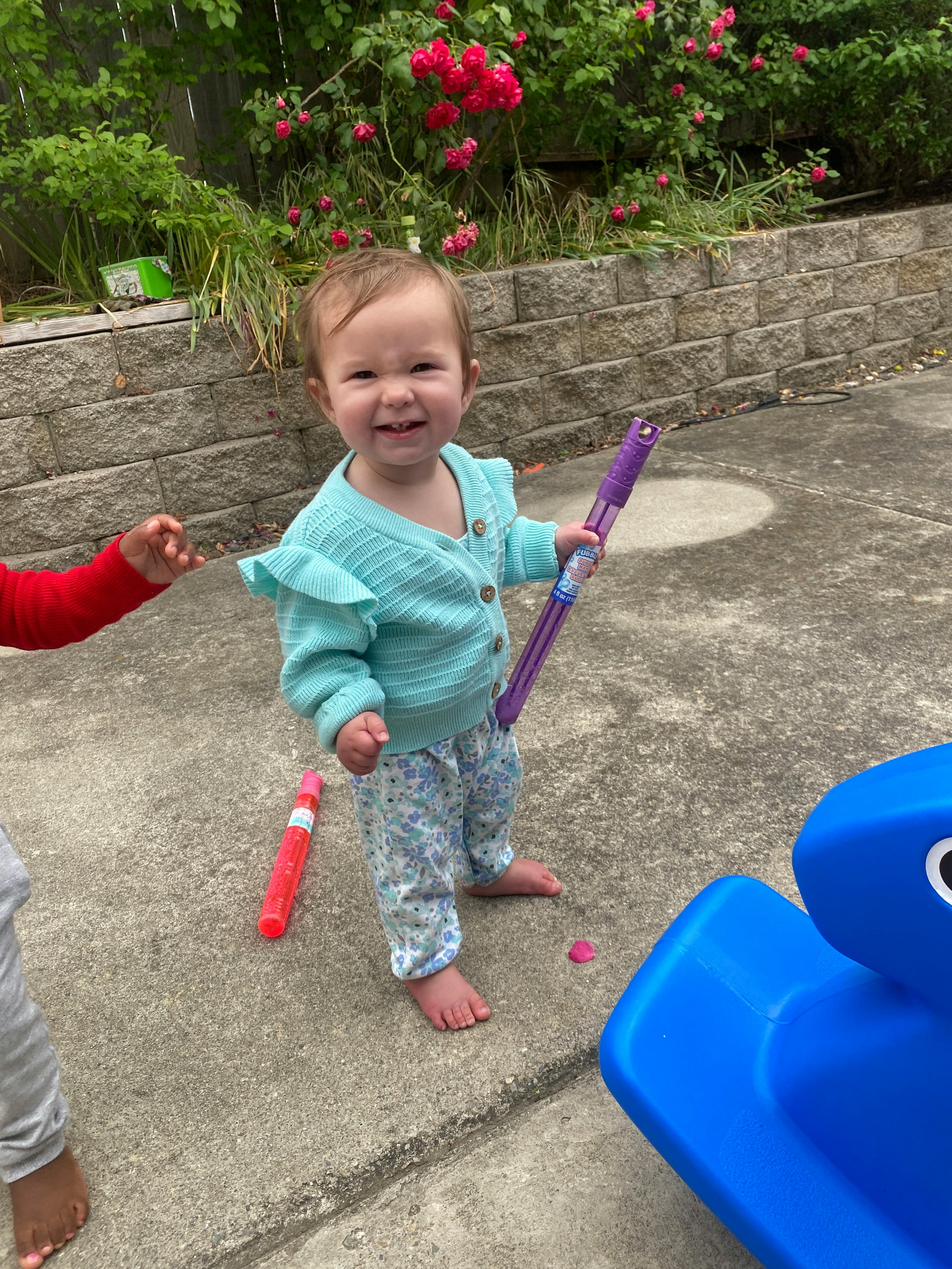 Child sitting on concrete ground holding a bubble wand