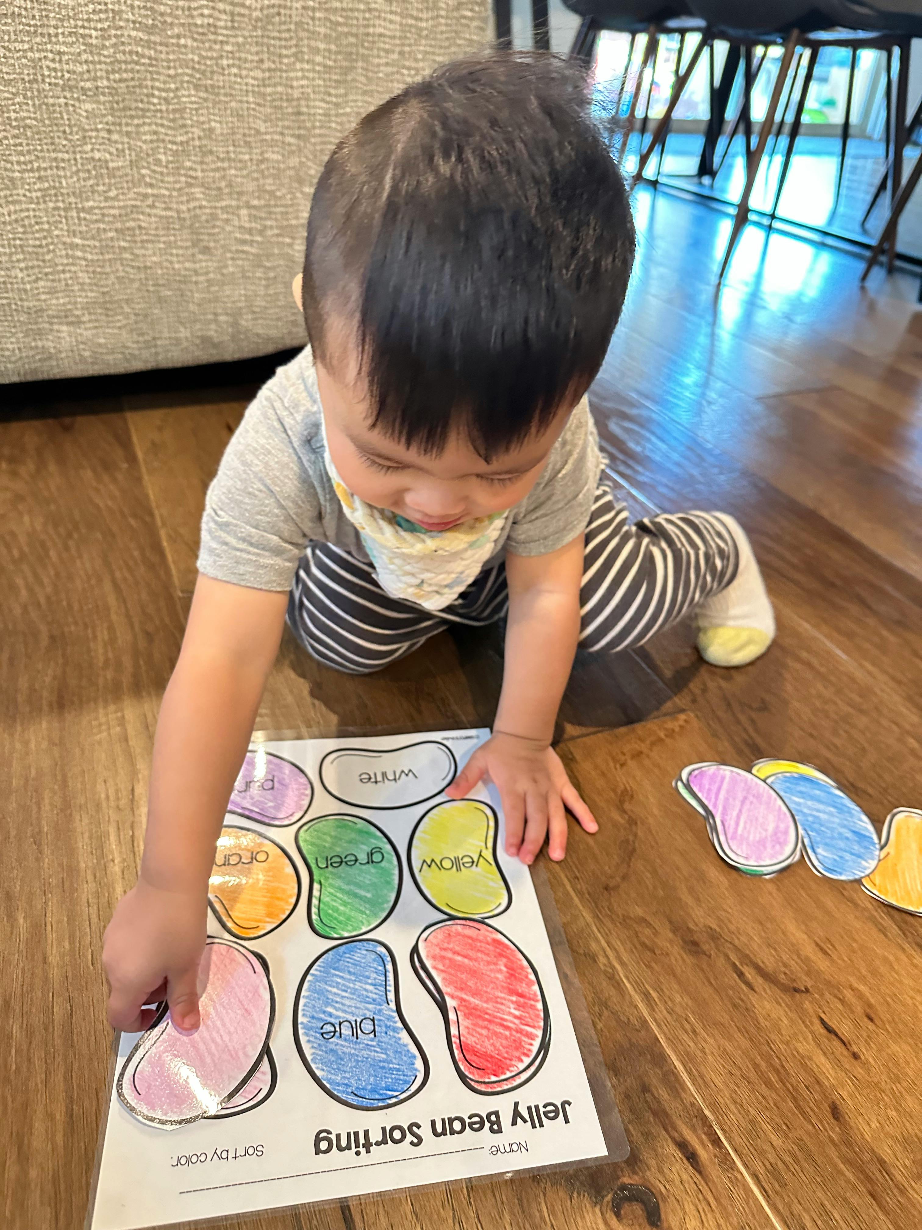 Child on floor playing with a jelly bean sorting activity