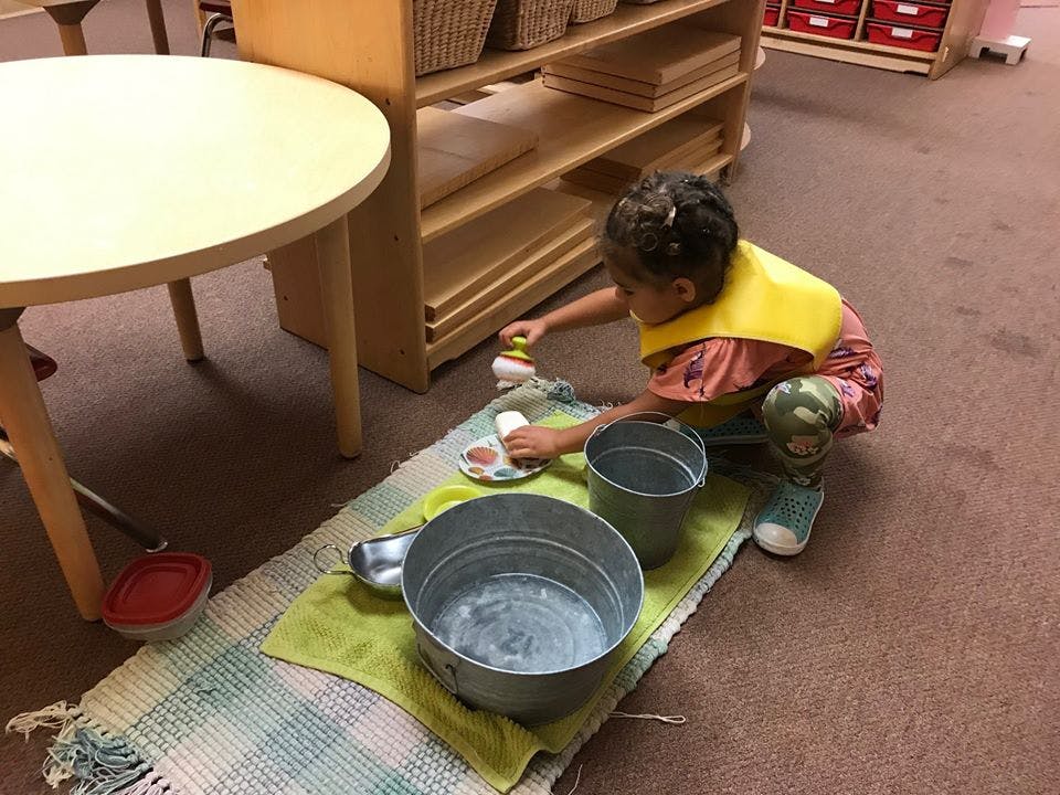 Child washing dishes in a classroom