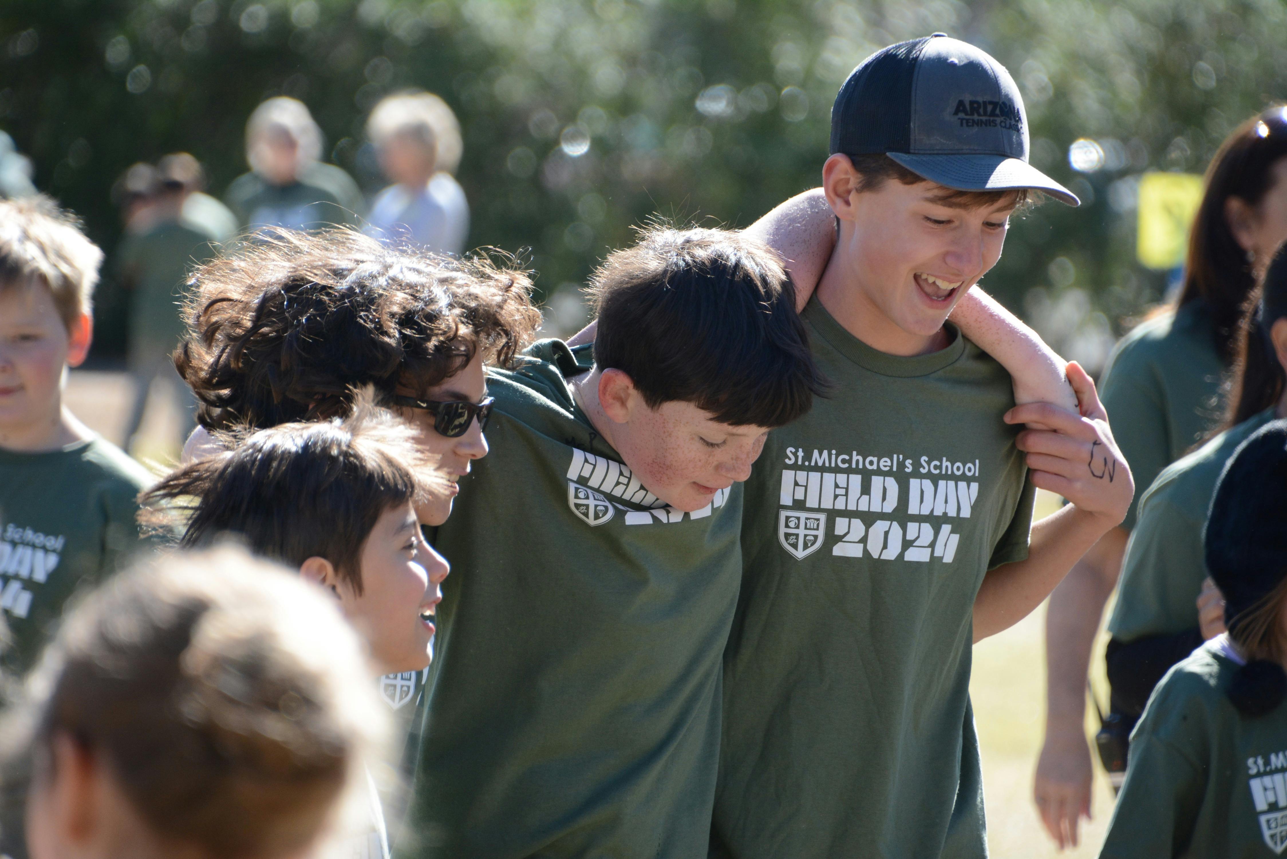Teen with arm around child wearing "St Michael's School Field Day 2024" shirt