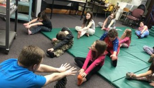 Group of children stretching on mats in a room