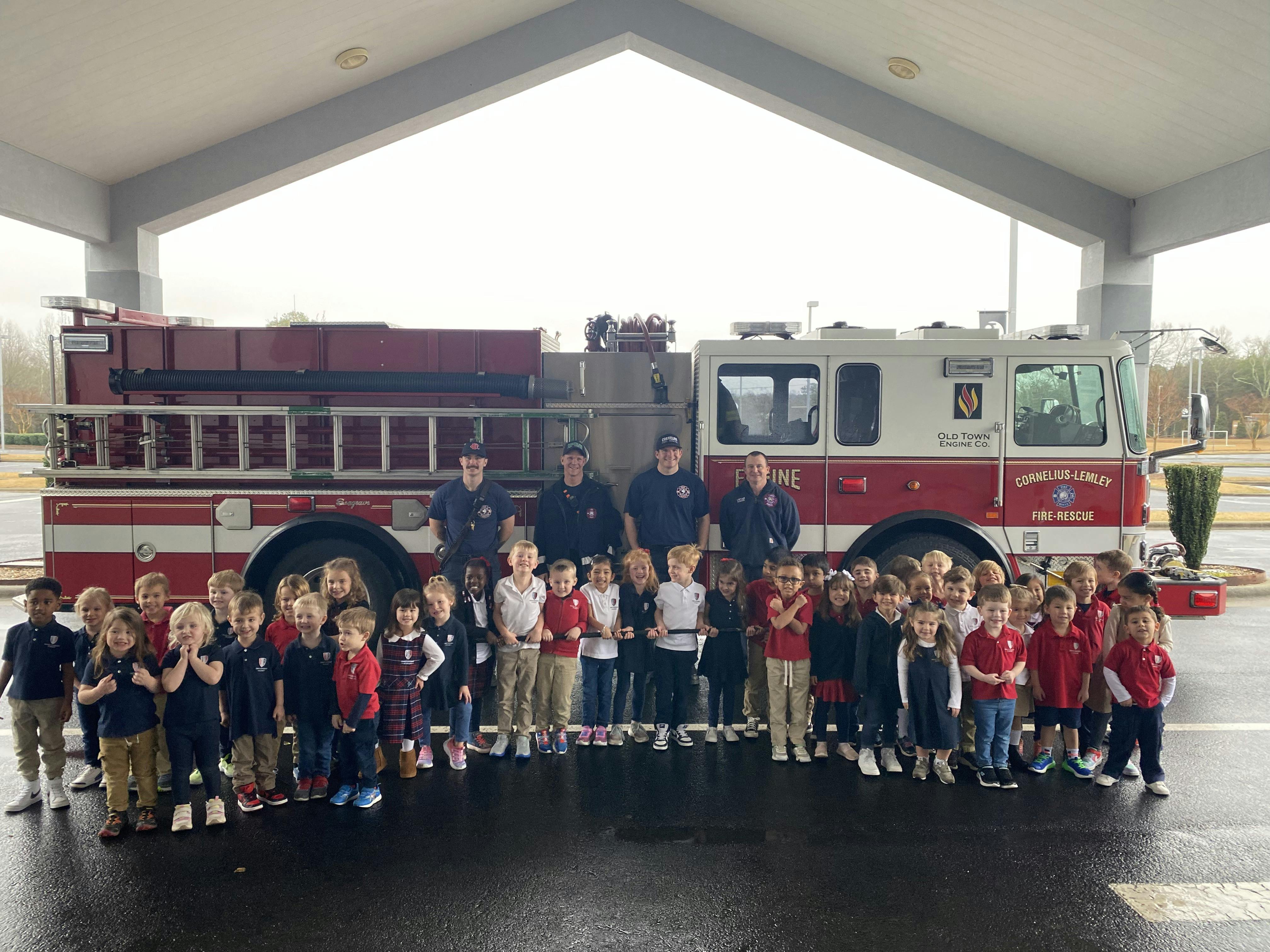Group of children and adults standing in front of a fire truck