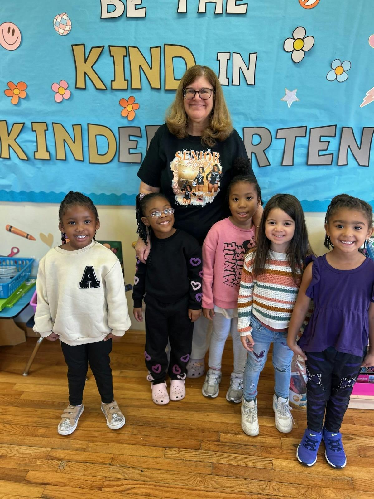 Teacher posing with five young children in a classroom