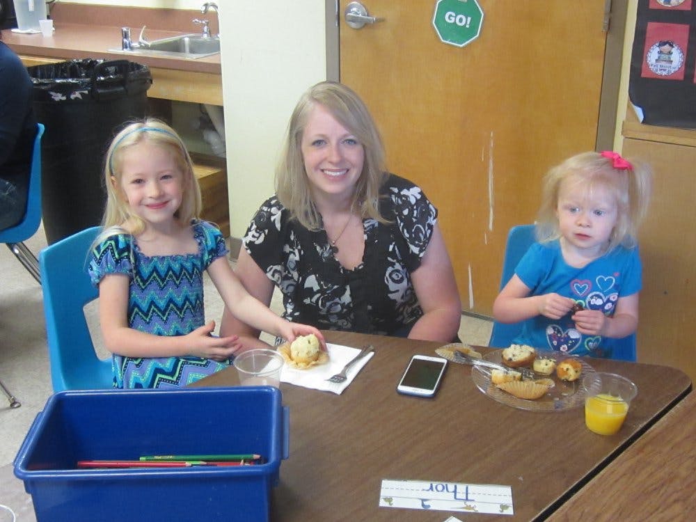 Adult and two children sitting at a table with food