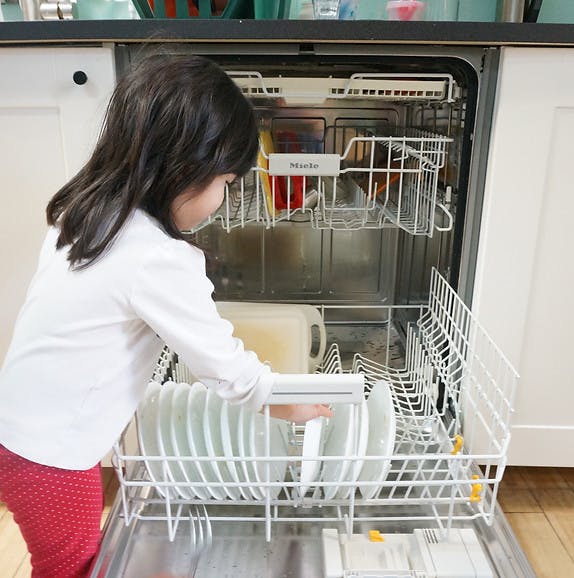 Child loading plates into a dishwasher