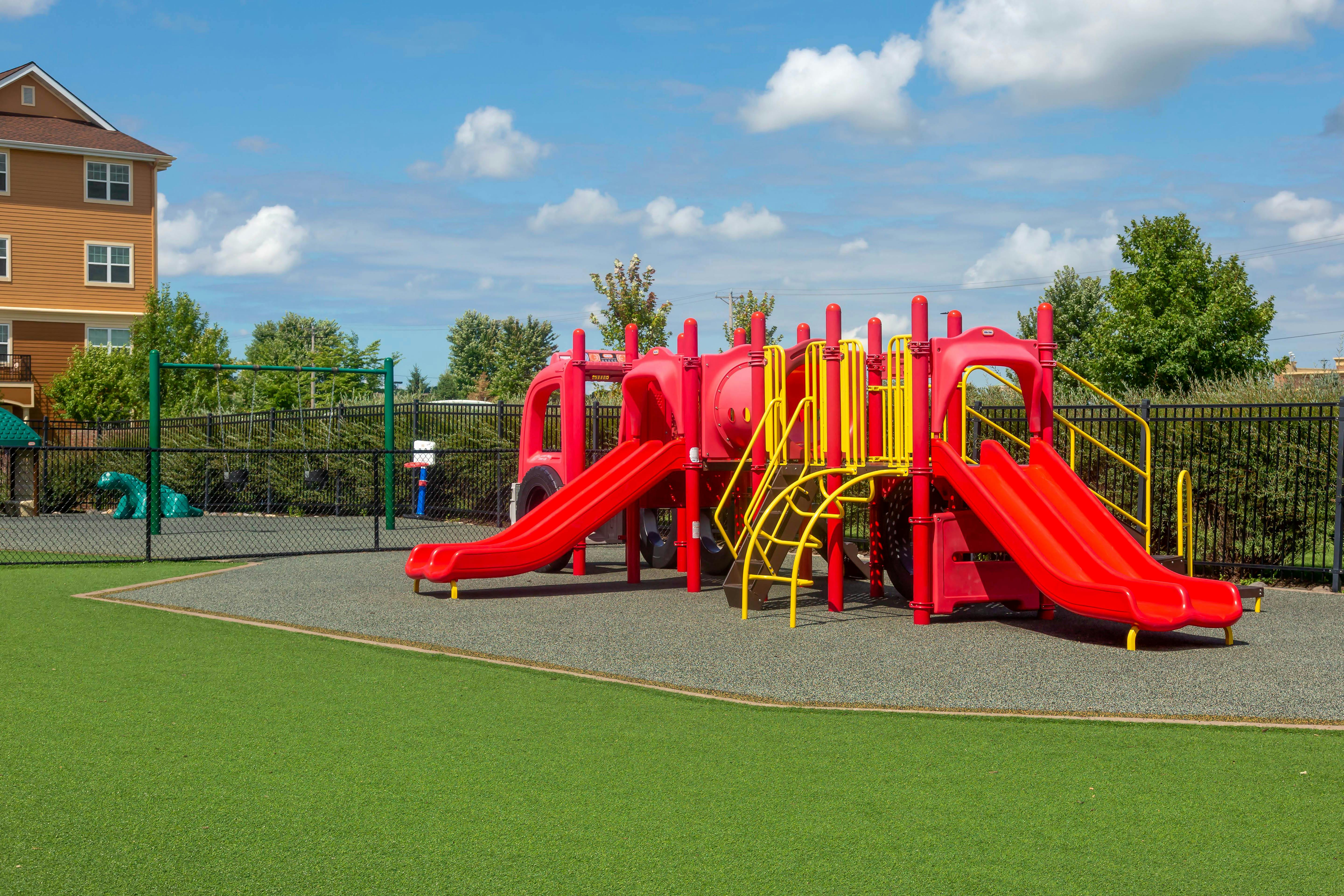 Red and yellow playground structure with slides on a sunny day