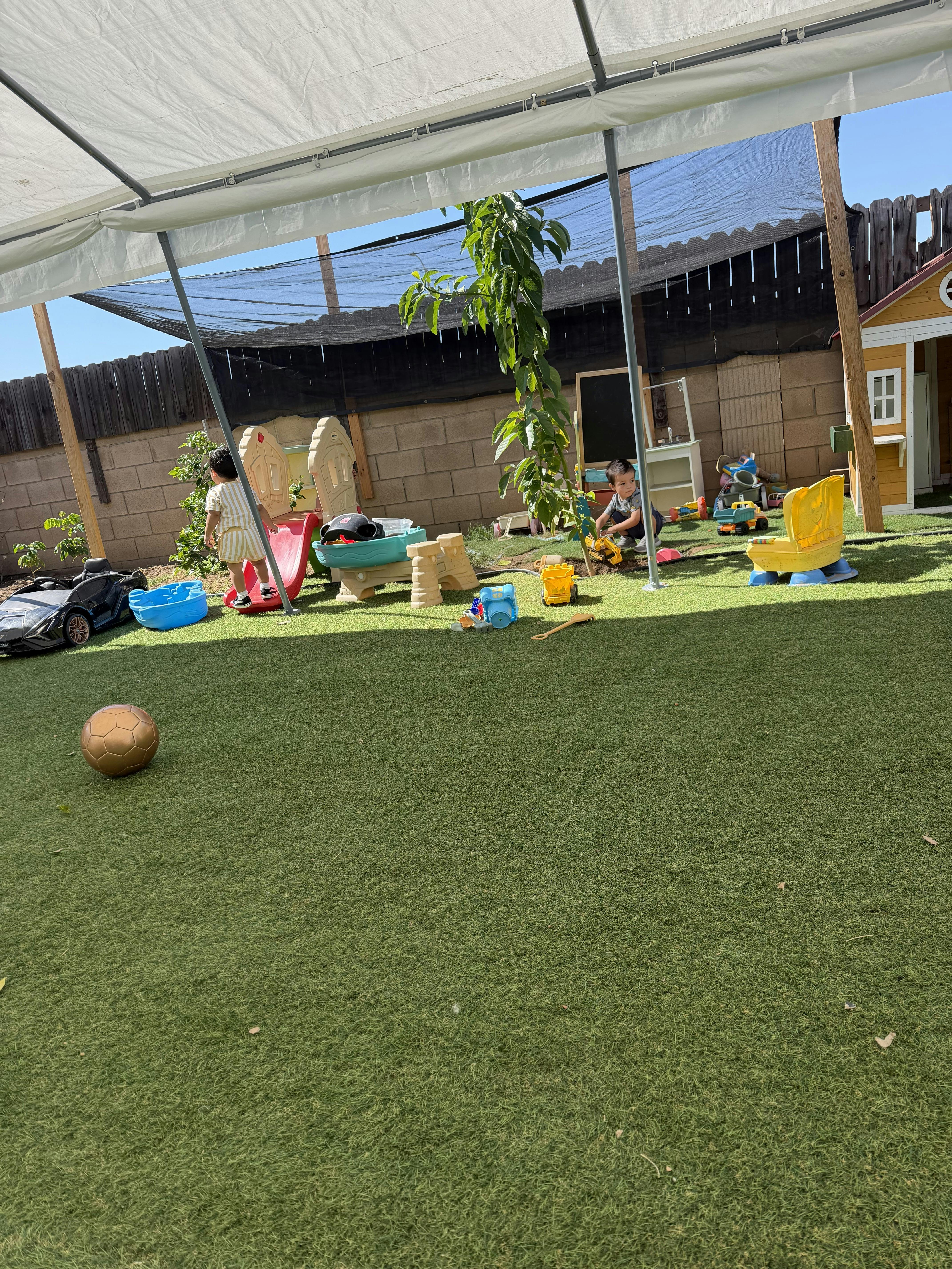 Children playing with toys in an outdoor yard with artificial turf