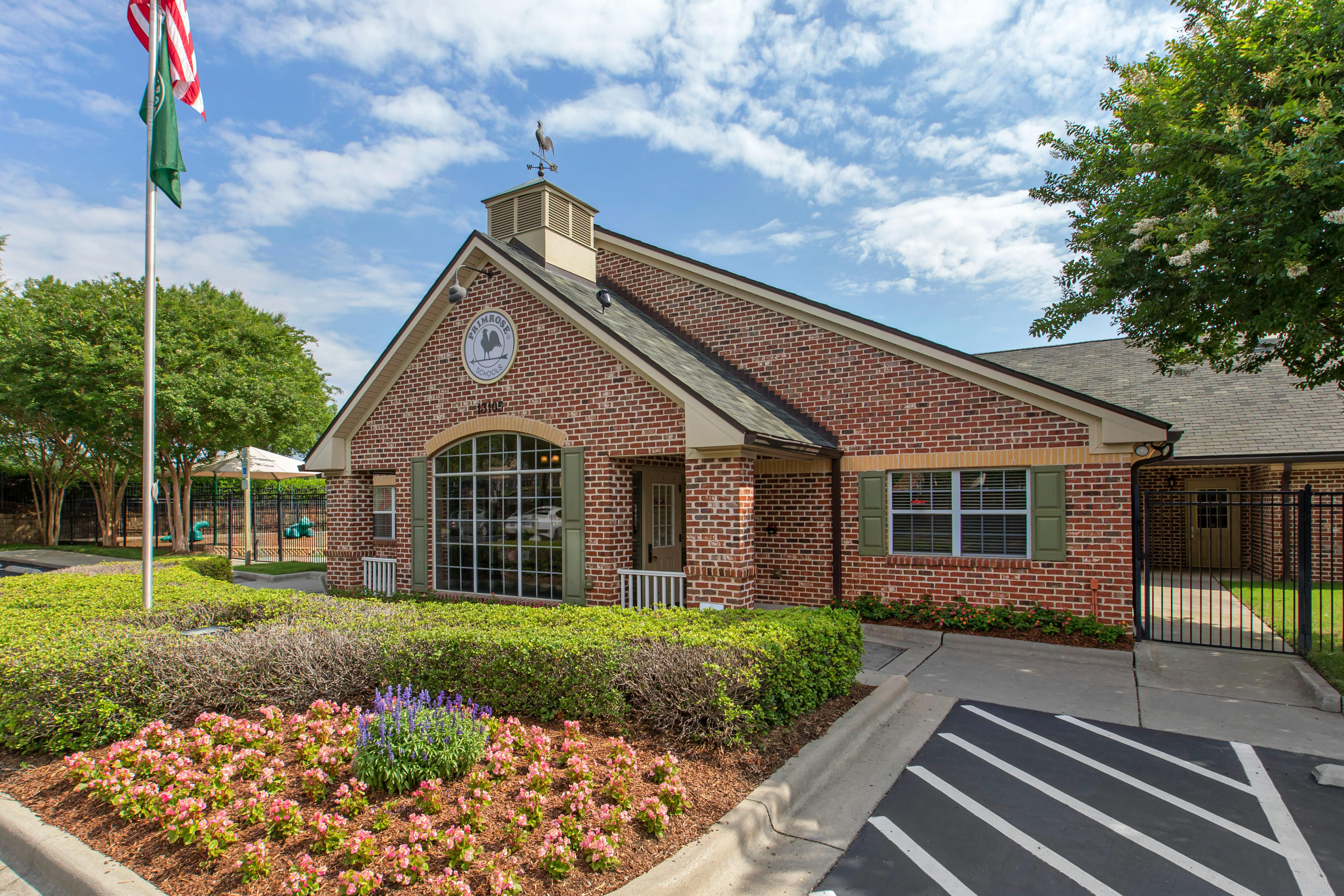 Brick building with a large arched window and a sign that says Primrose Schools
