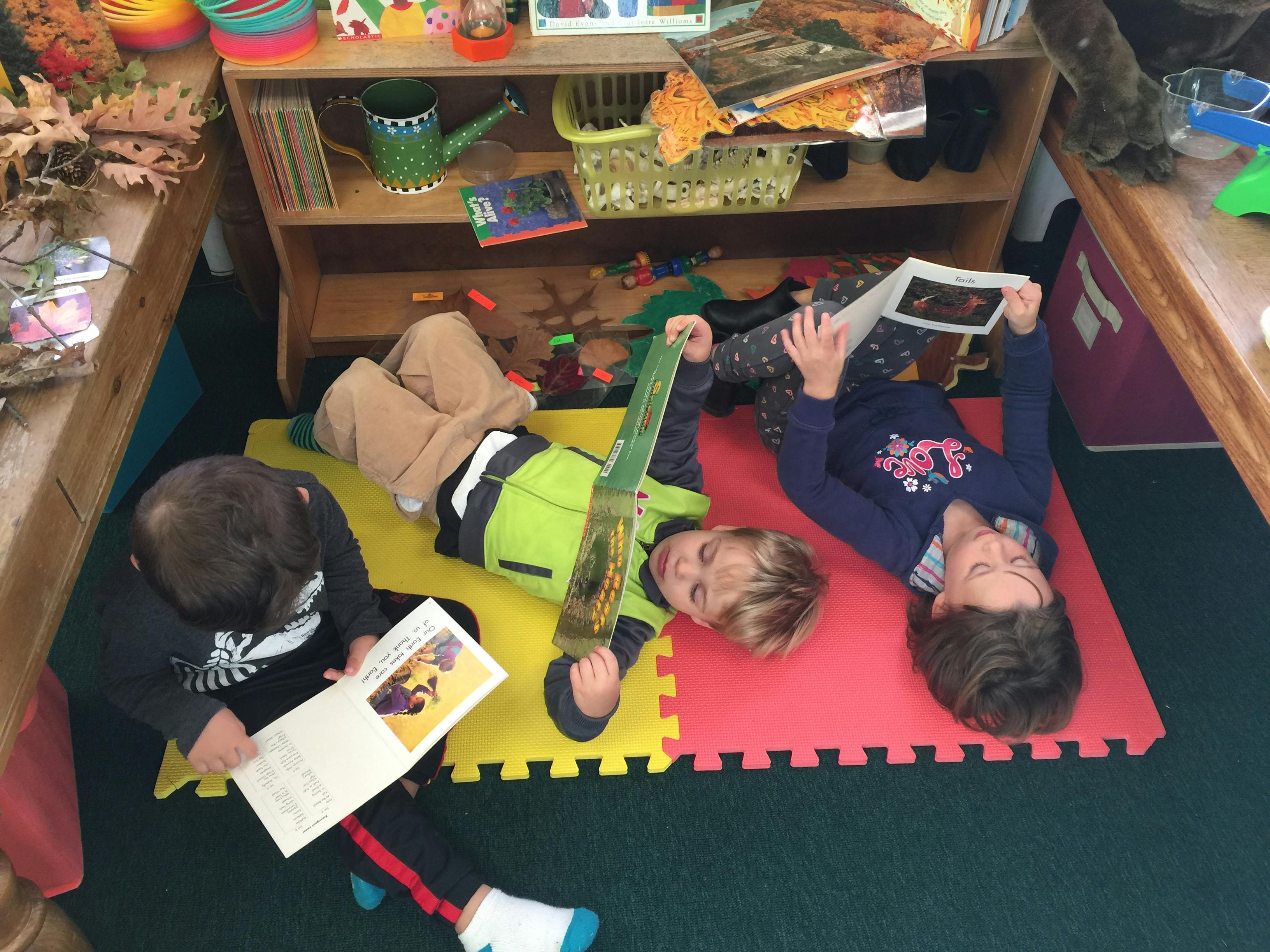 Three children reading books on the floor