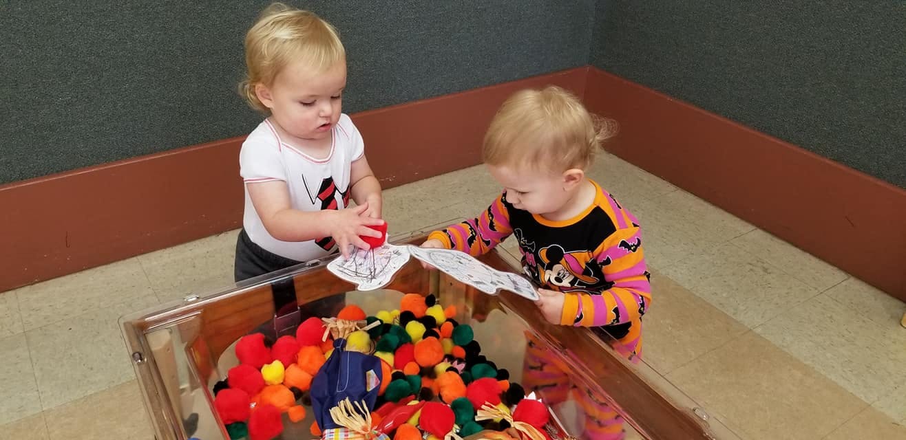 Two children playing with toys in a bin