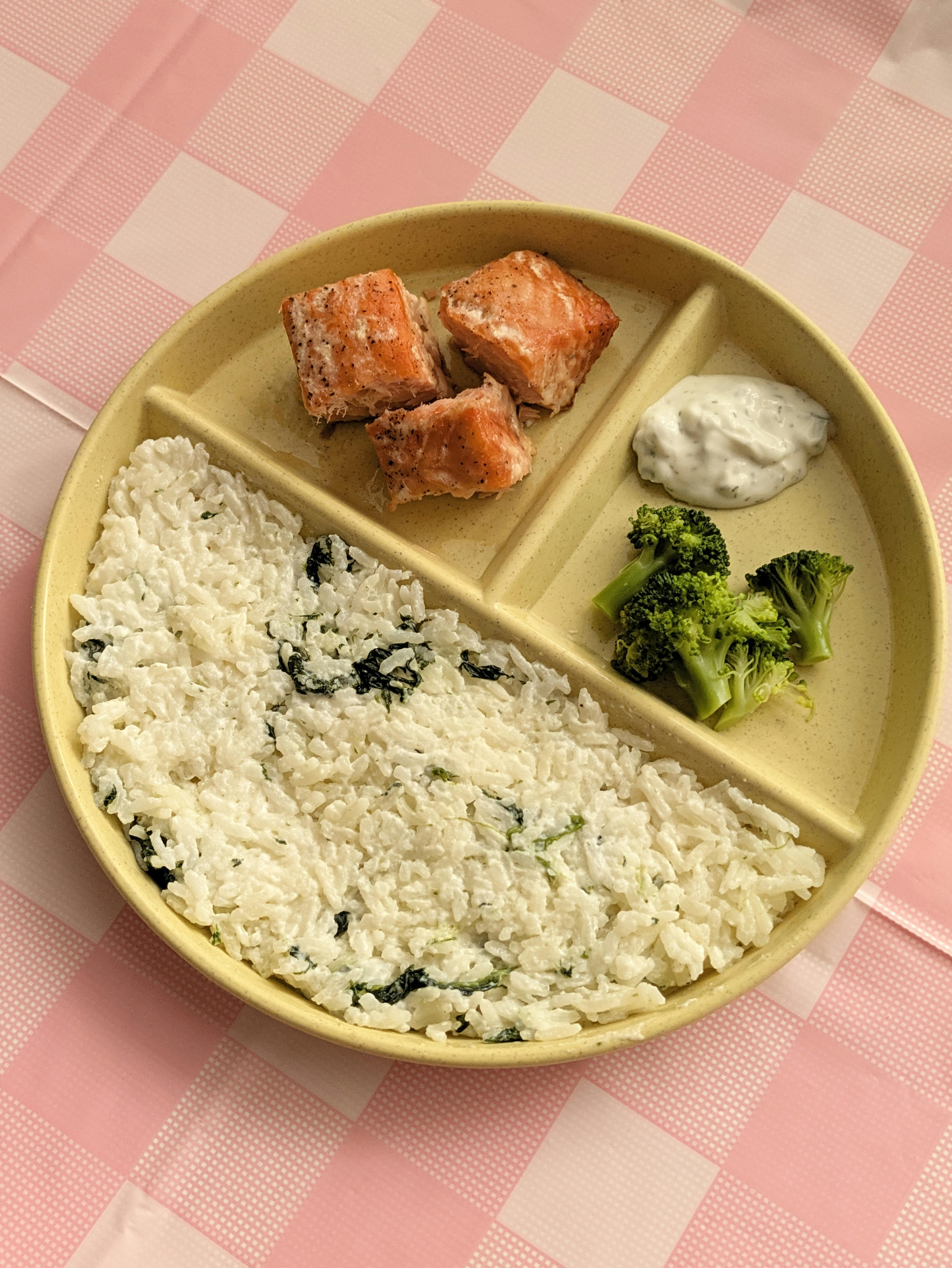 Portioned plate with salmon, broccoli, rice with greens, and sauce
