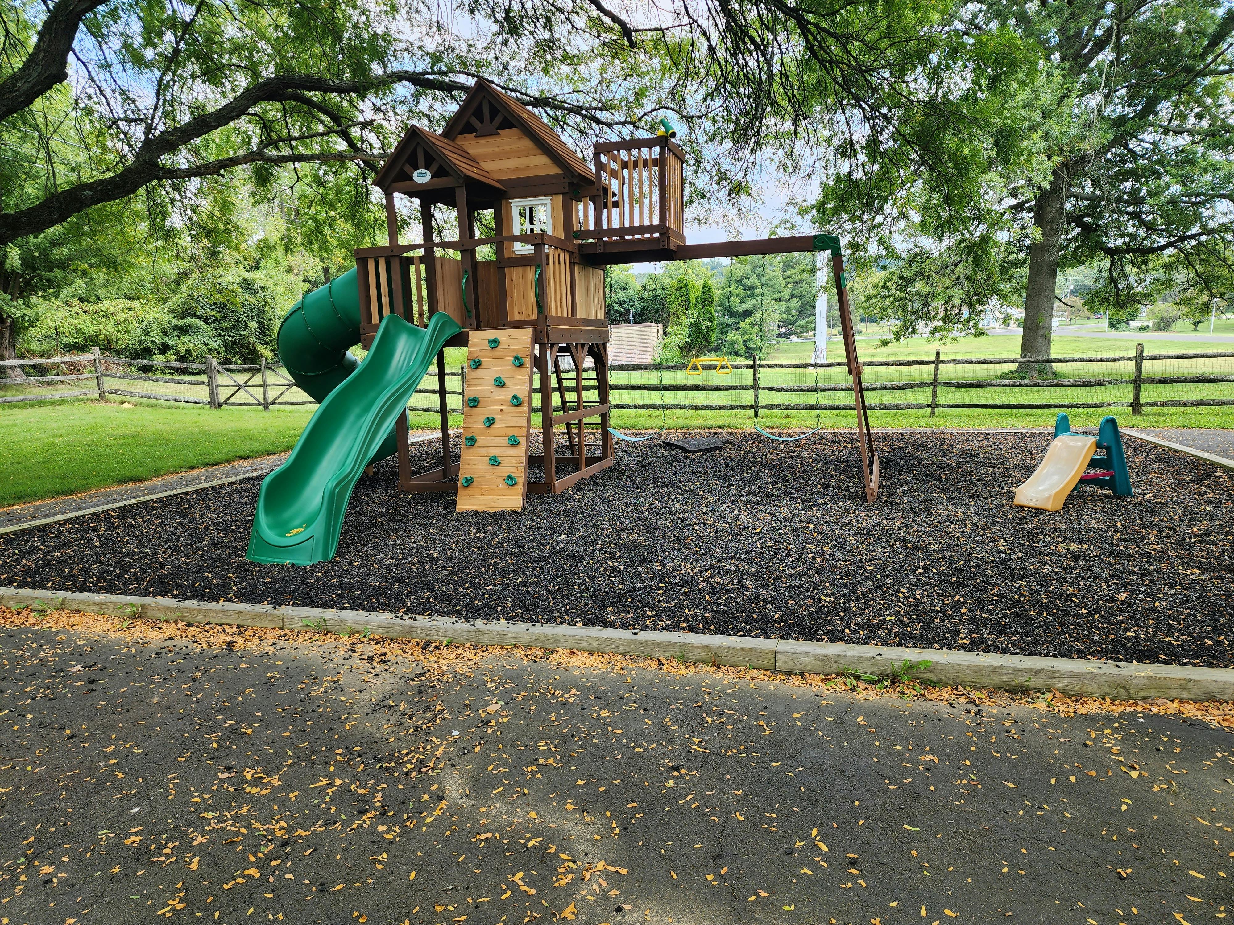 Playground with a wooden playset, green slide, and small yellow slide