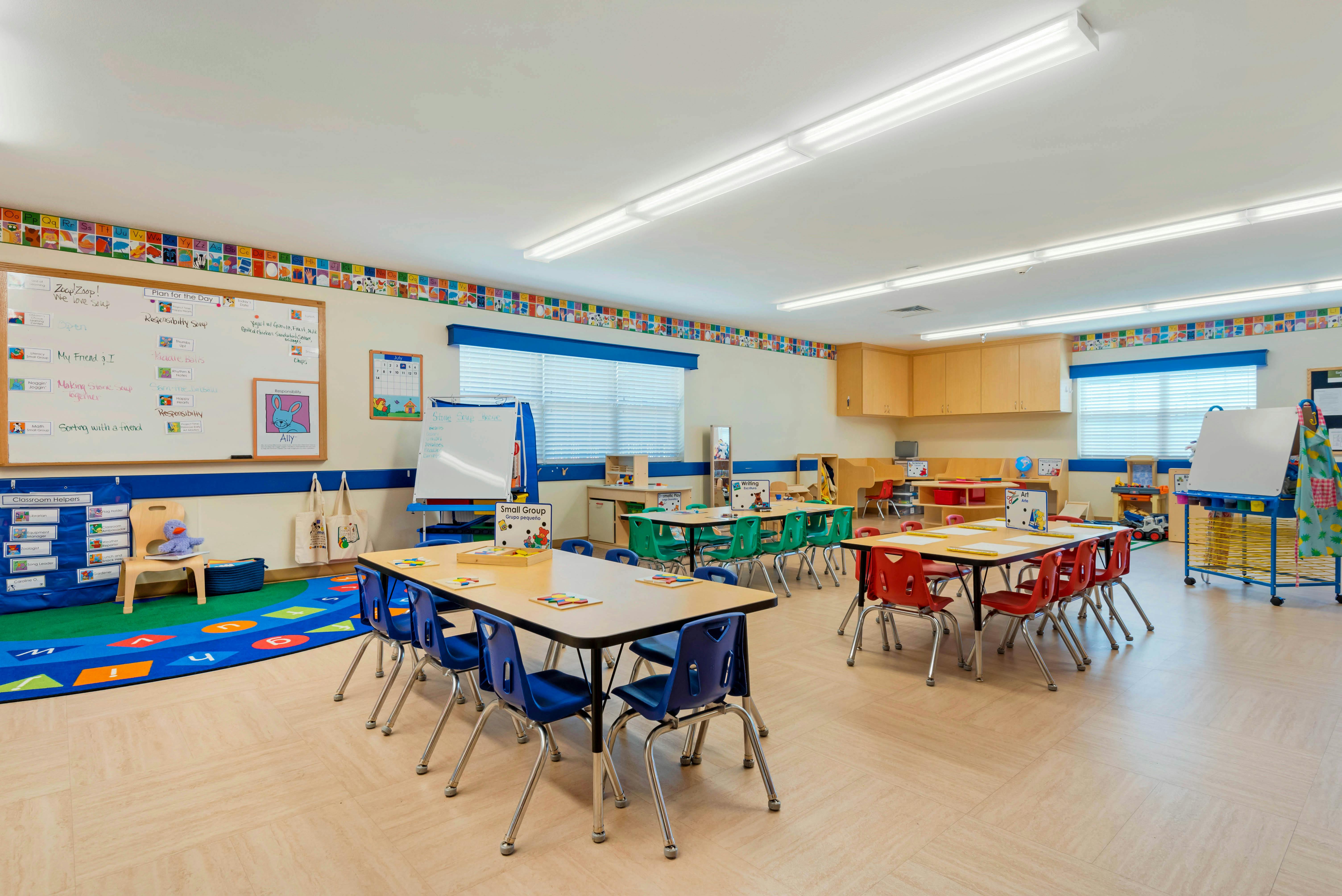 Classroom with child-sized tables and chairs, whiteboards, and learning decorations