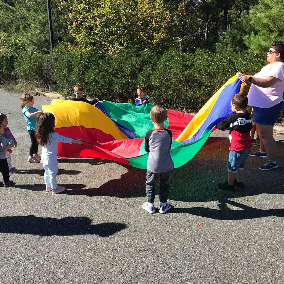 Children and an adult playing with a colorful parachute outdoors