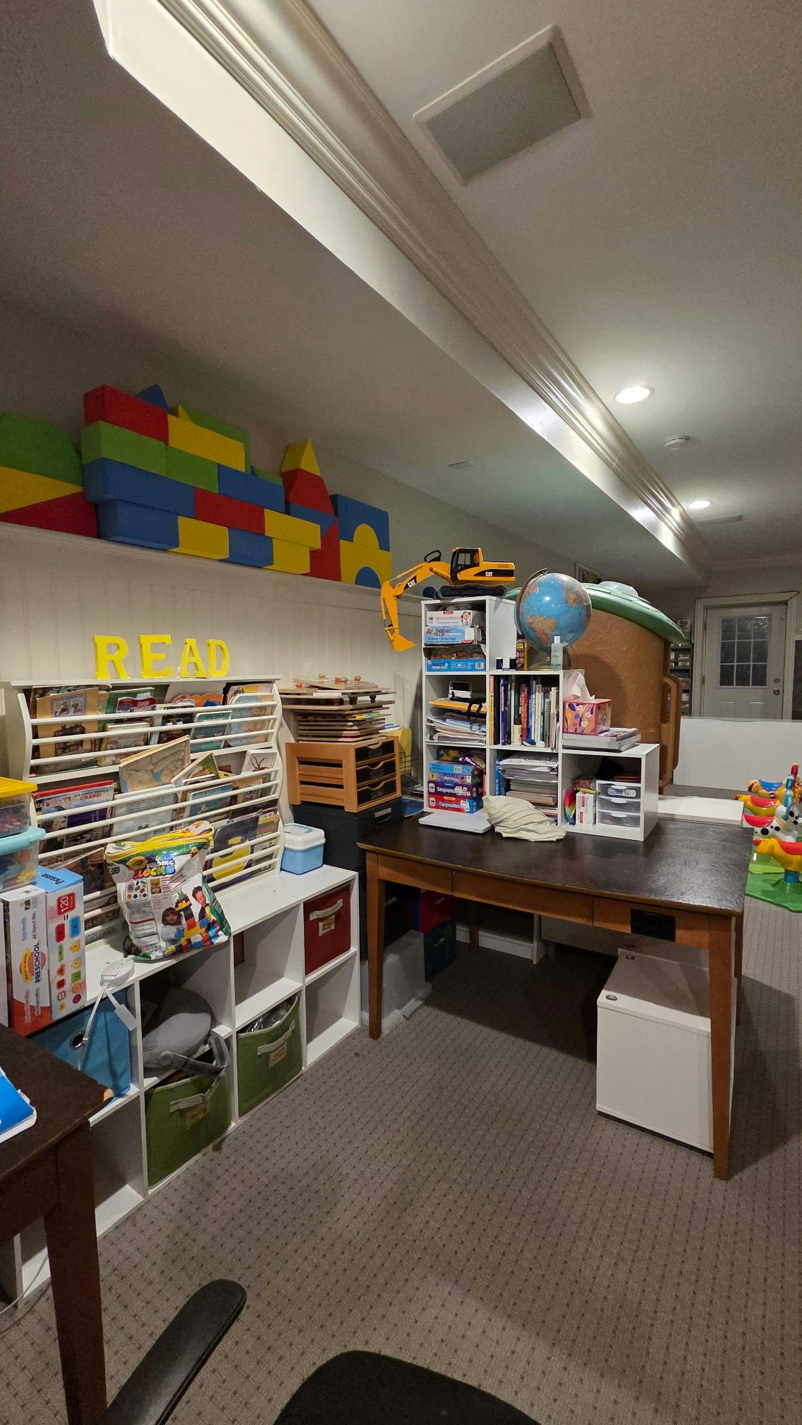 Playroom with shelves of books and toys, a desk, and large building blocks