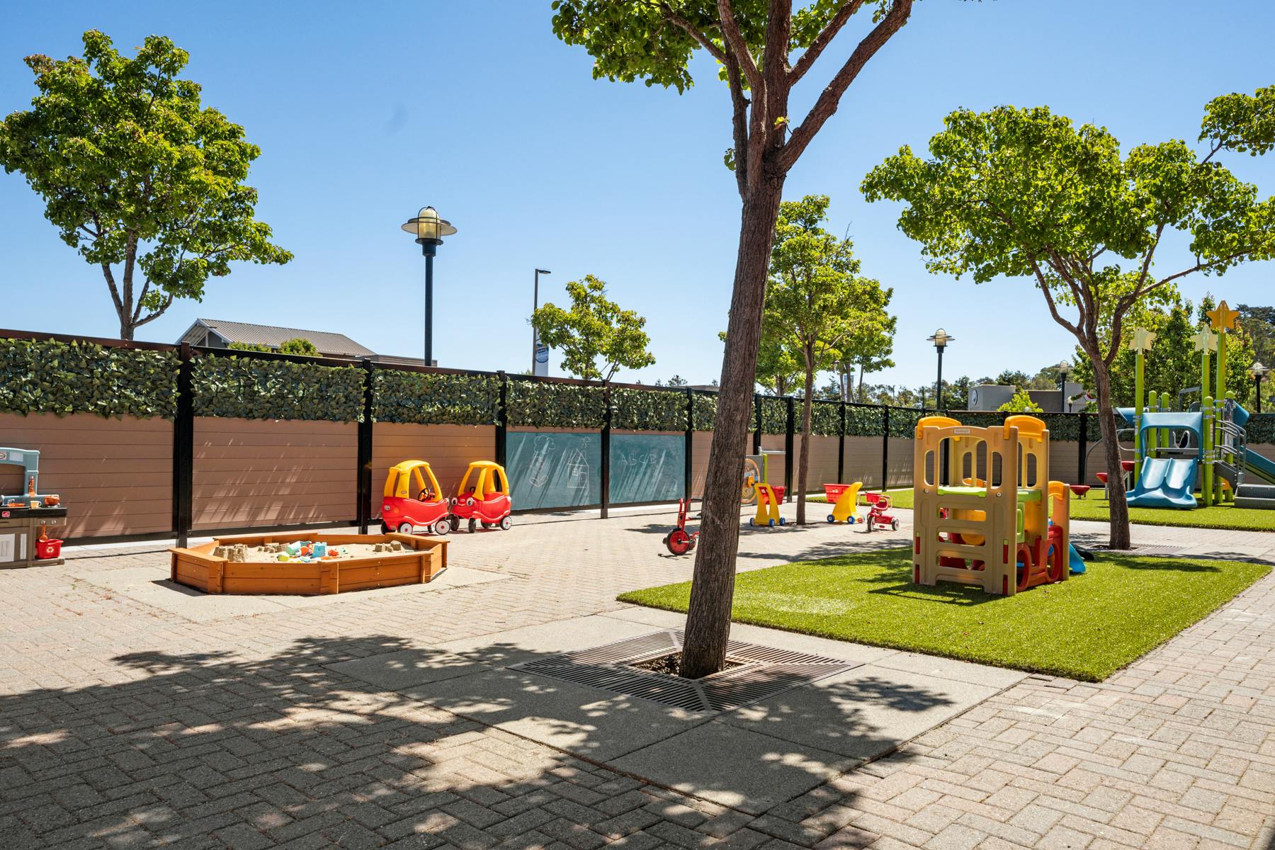 Outdoor playground with sandpit, play structure, and swings