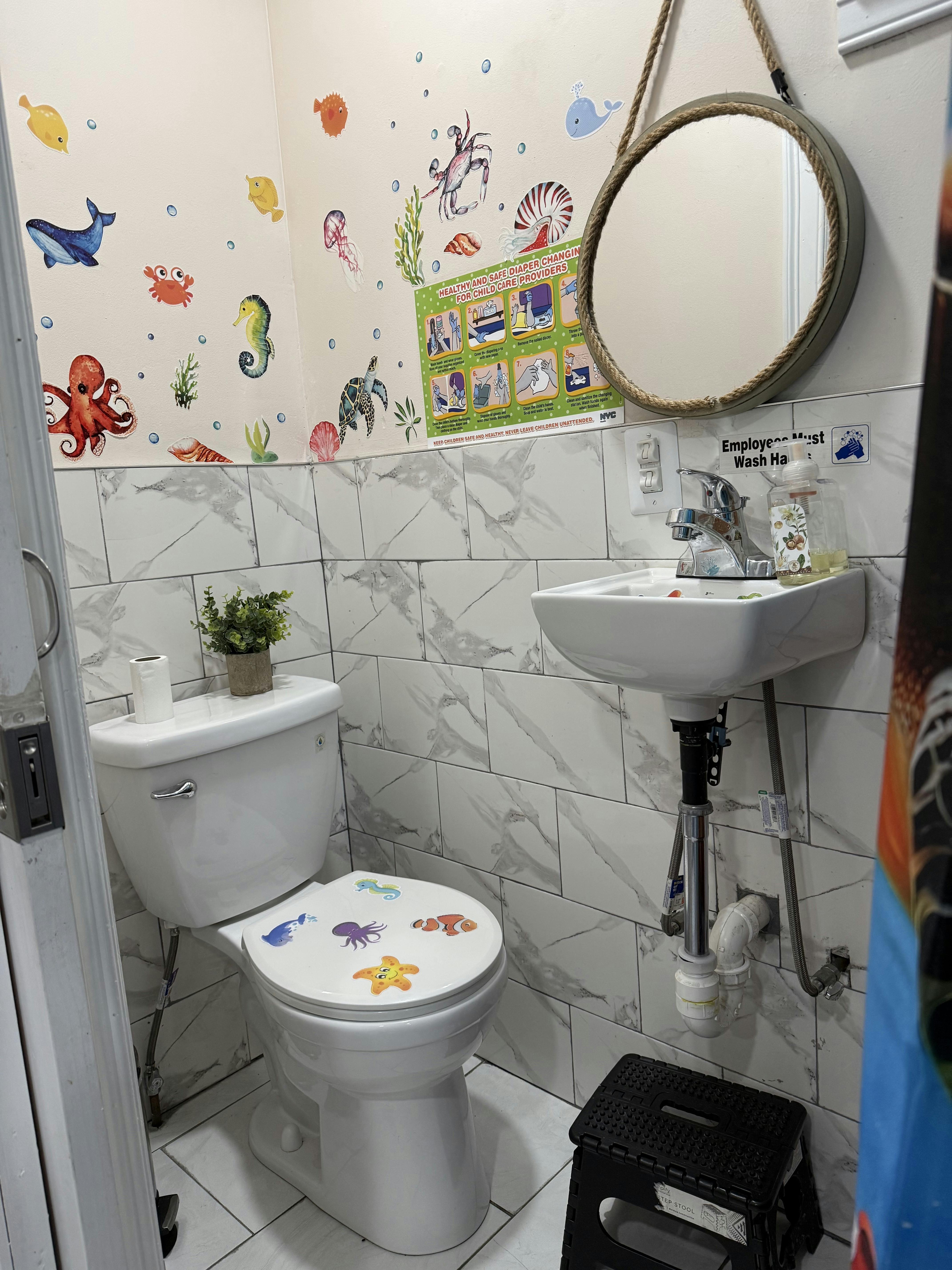 Bathroom with toilet, sink, mirror, and sea creature wall decals