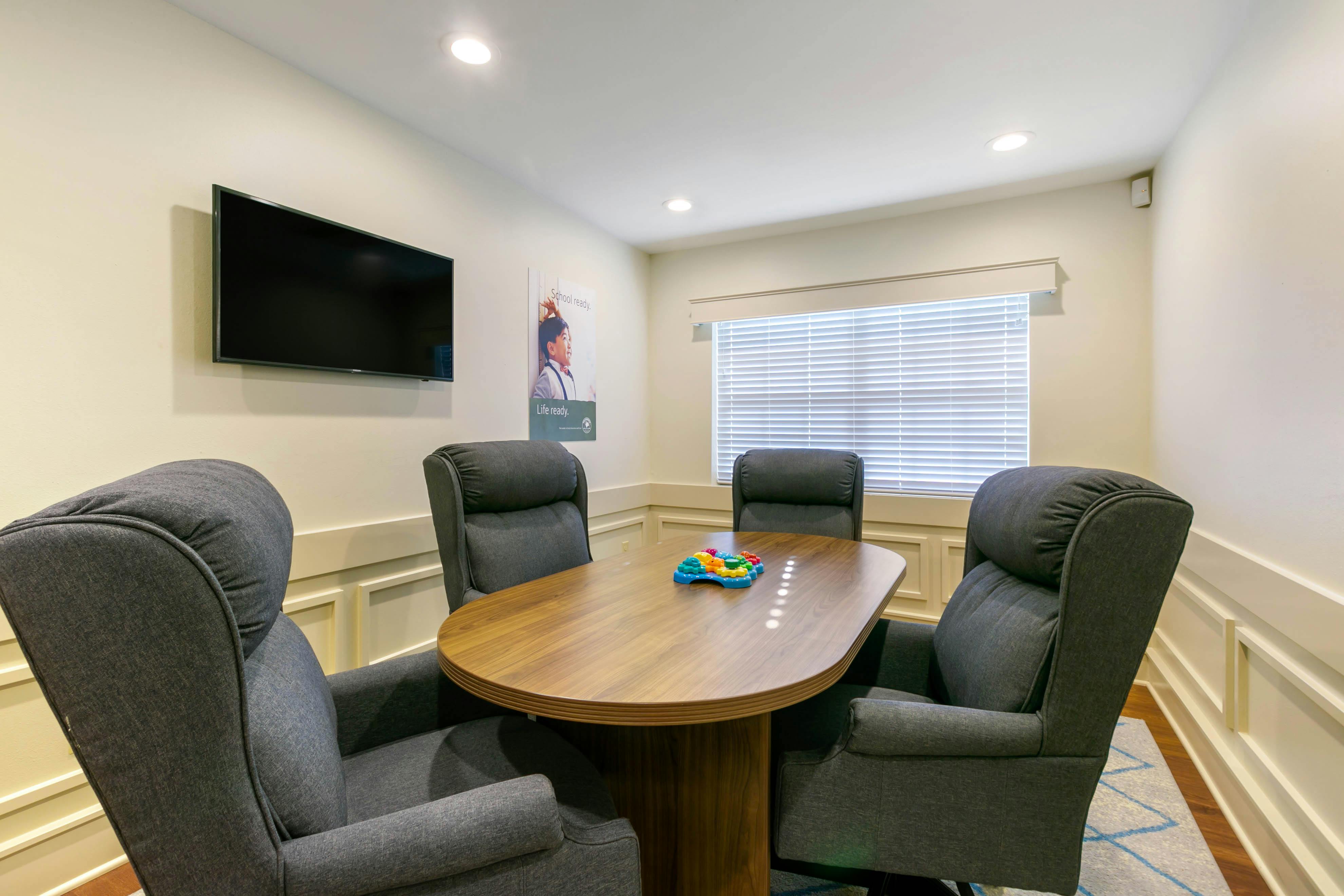 Meeting room with four chairs, a table, and a monitor on the wall