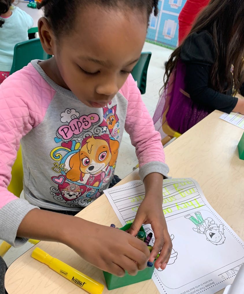 Child coloring at a desk in a classroom