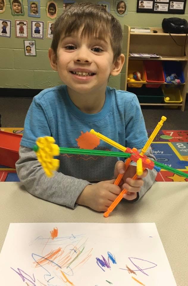 Child holding a colorful construction toy in a classroom