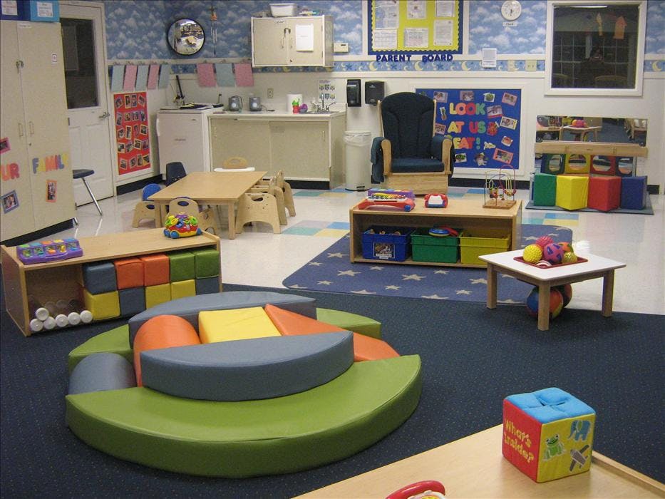 An empty early childhood classroom with colorful play areas and small furniture