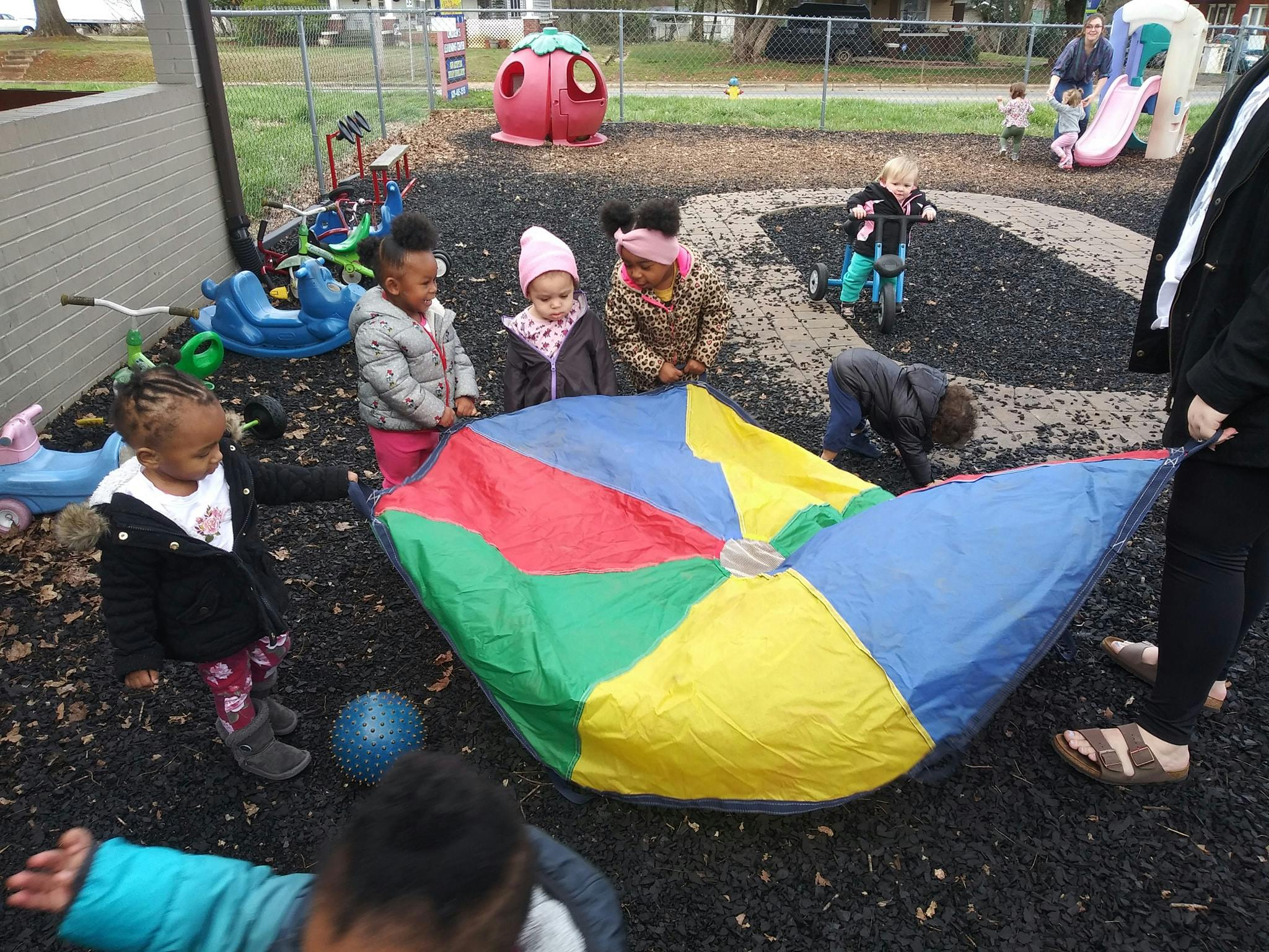 Children playing with a colorful parachute on a playground