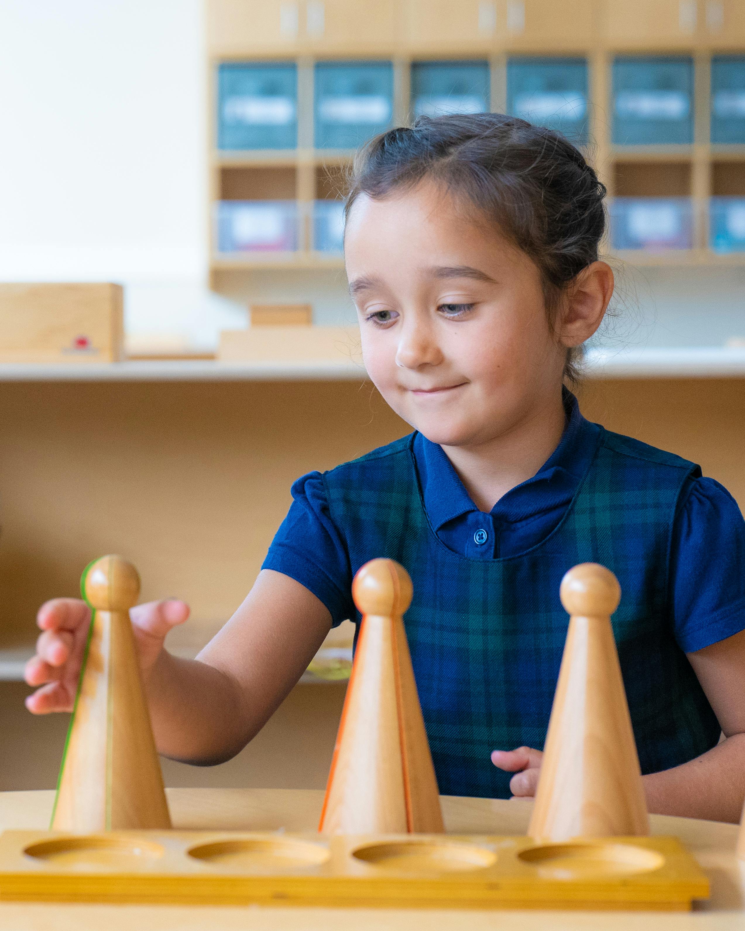 Child playing with wooden cones on a board