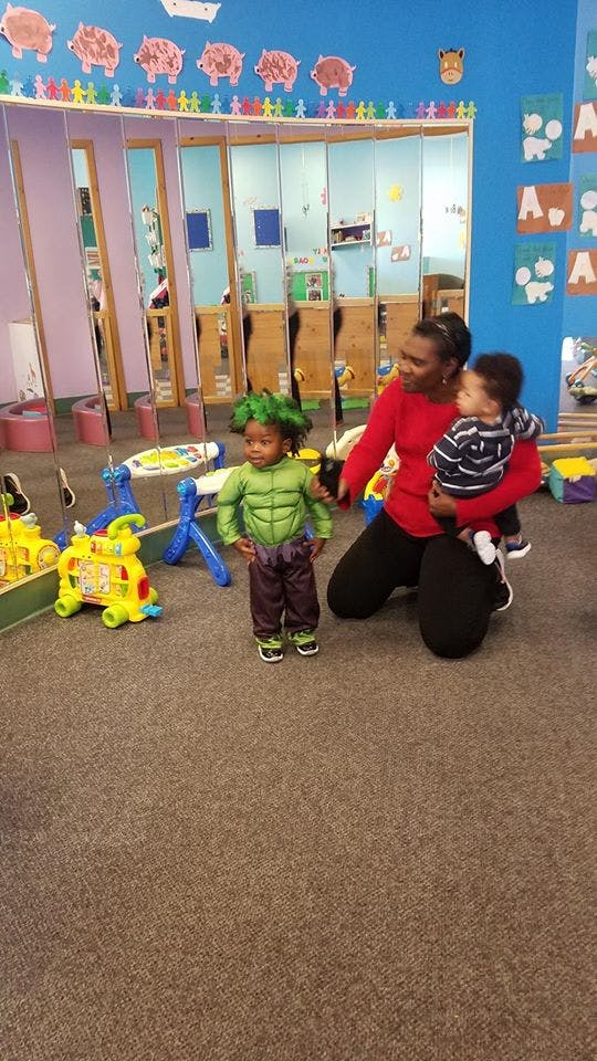 Person kneeling with a child in their arms and another child in a costume