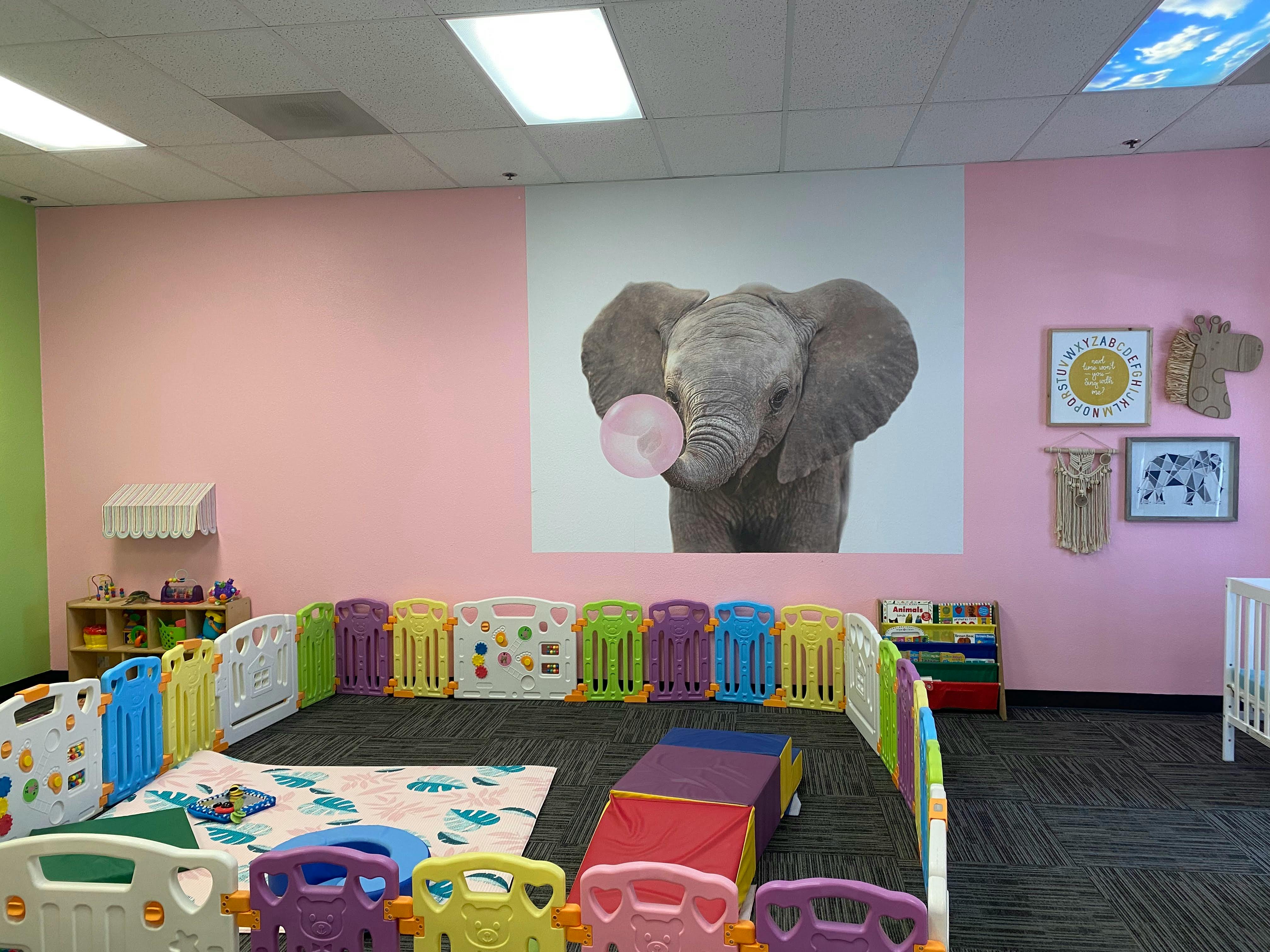Play area with colorful fence and elephant image on wall