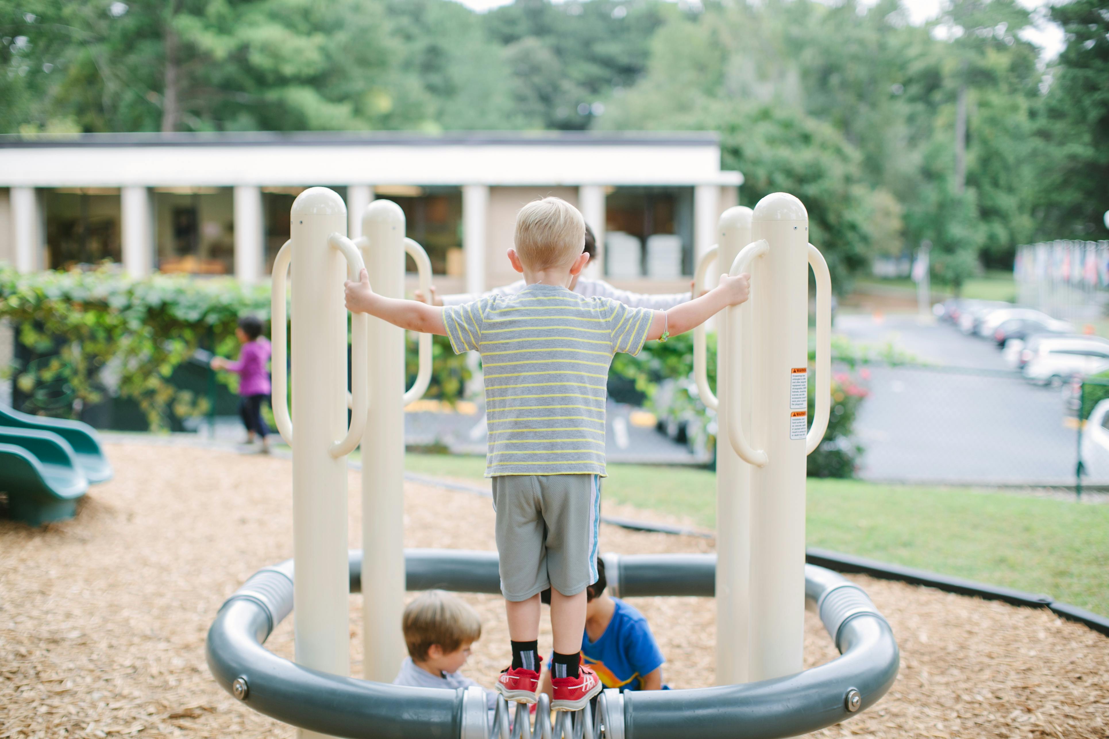 Child standing on playground equipment with arms outstretched