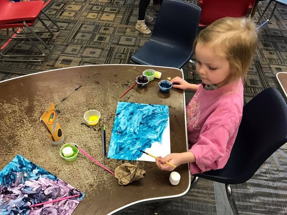 Child painting a blue picture at a table