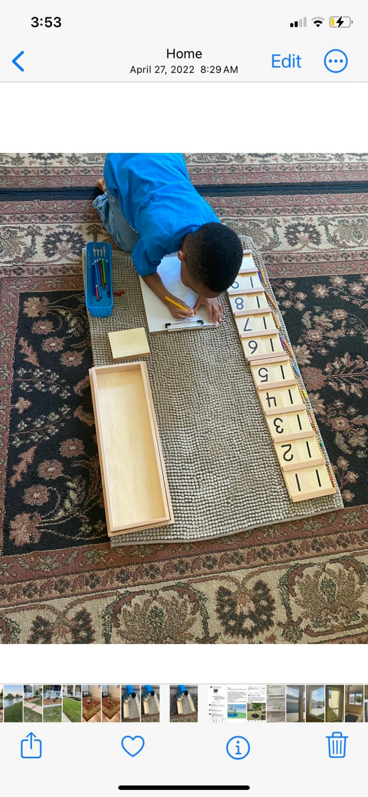 Child writing on paper with number blocks on wooden blocks