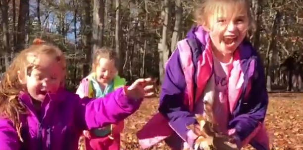 Three children playing outdoors in autumn leaves