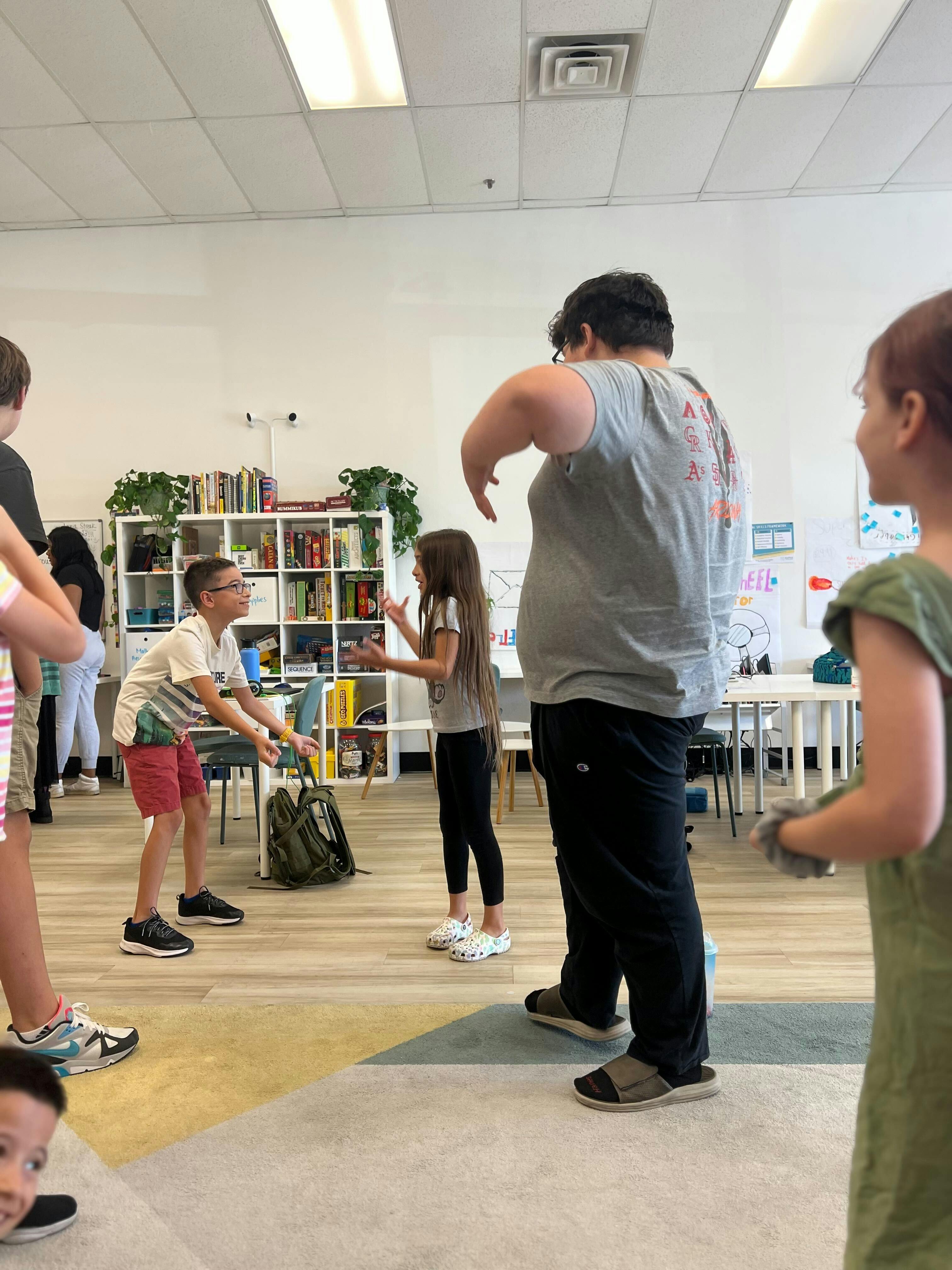 People standing in a room, two children facing each other