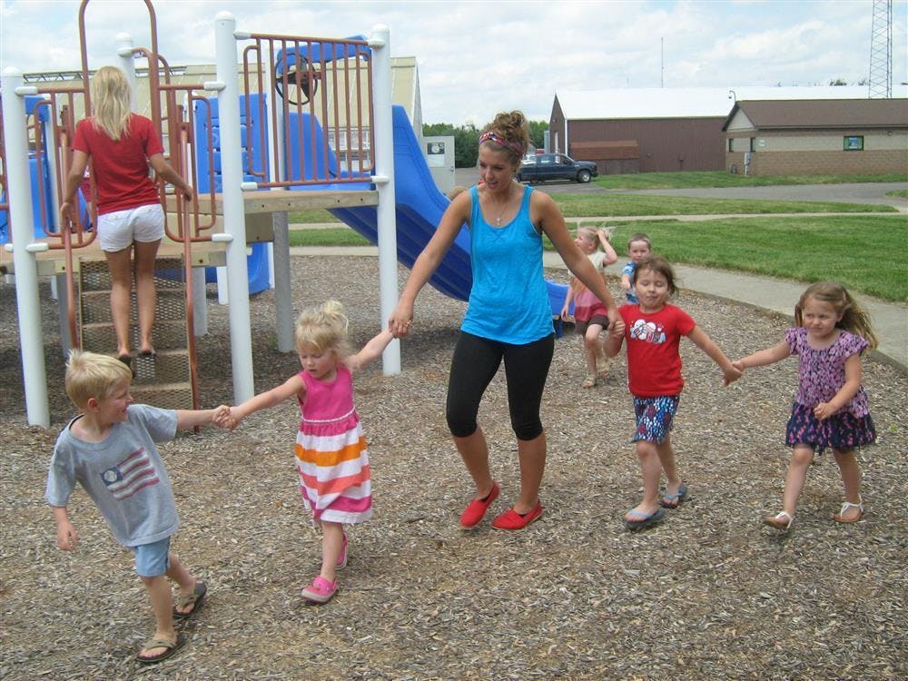 Adult and children holding hands on a playground