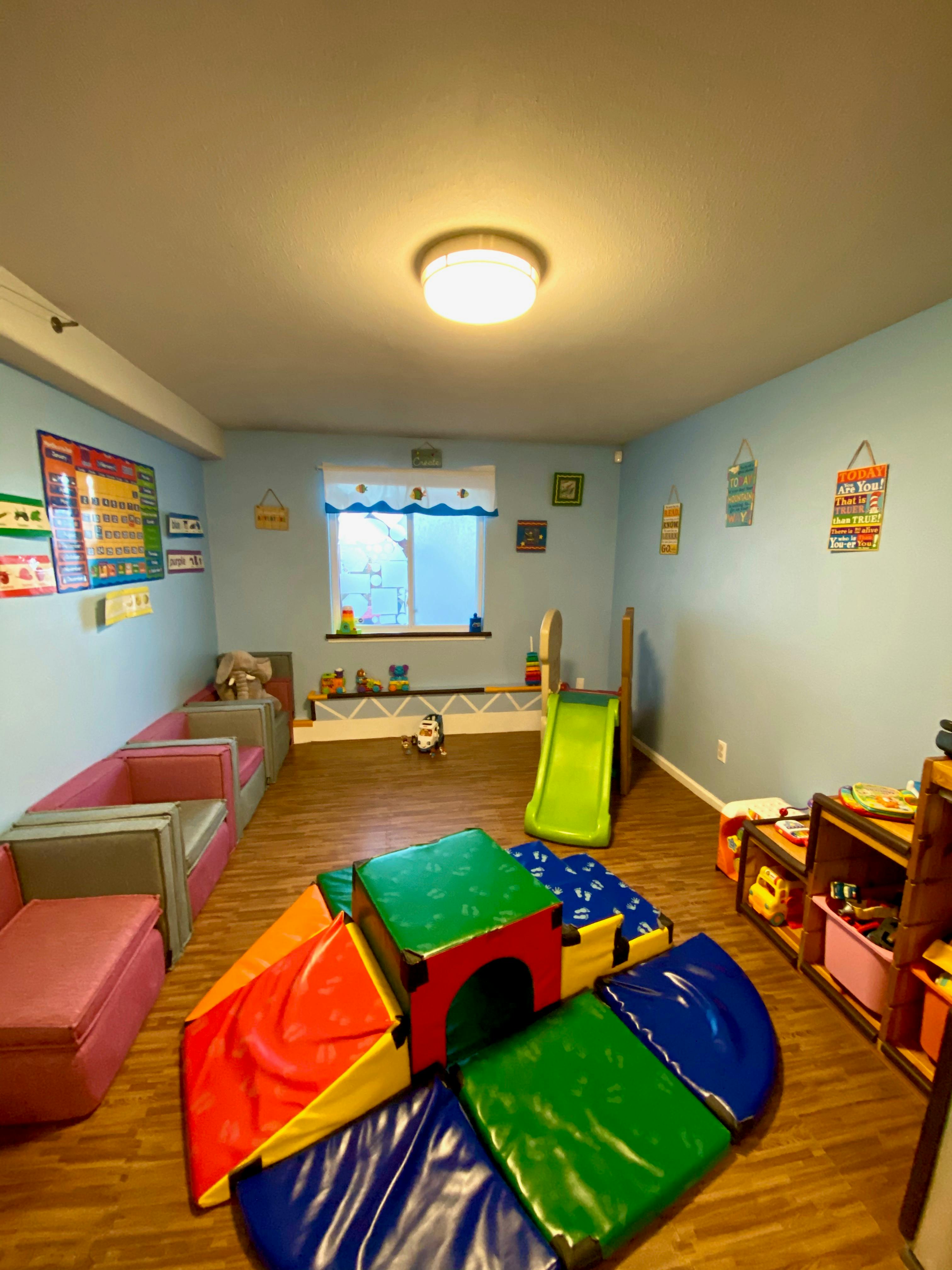 Indoor play area with soft play equipment, a small slide, and seating