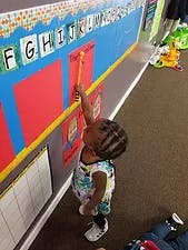 Child reaching up to touch letters on a wall