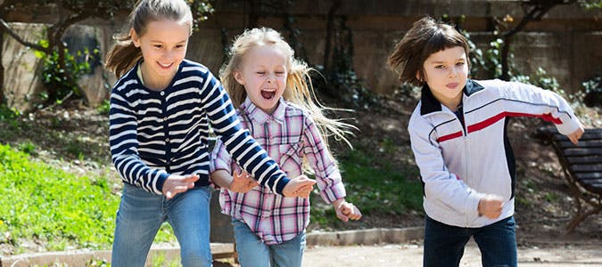 Three children running outdoors