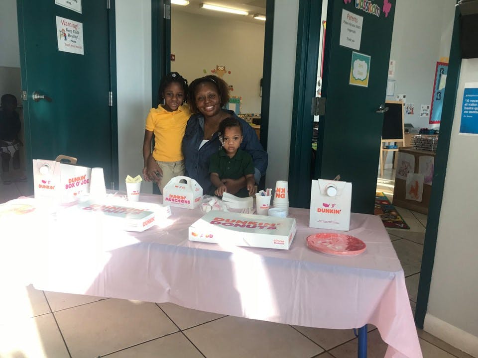 Person and two children standing behind a table with food items