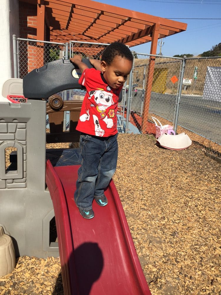 Child standing on a red slide on a playground