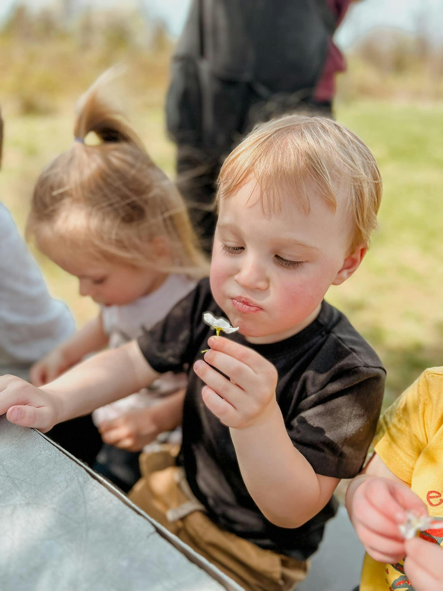 Child holding a small white flower to their mouth