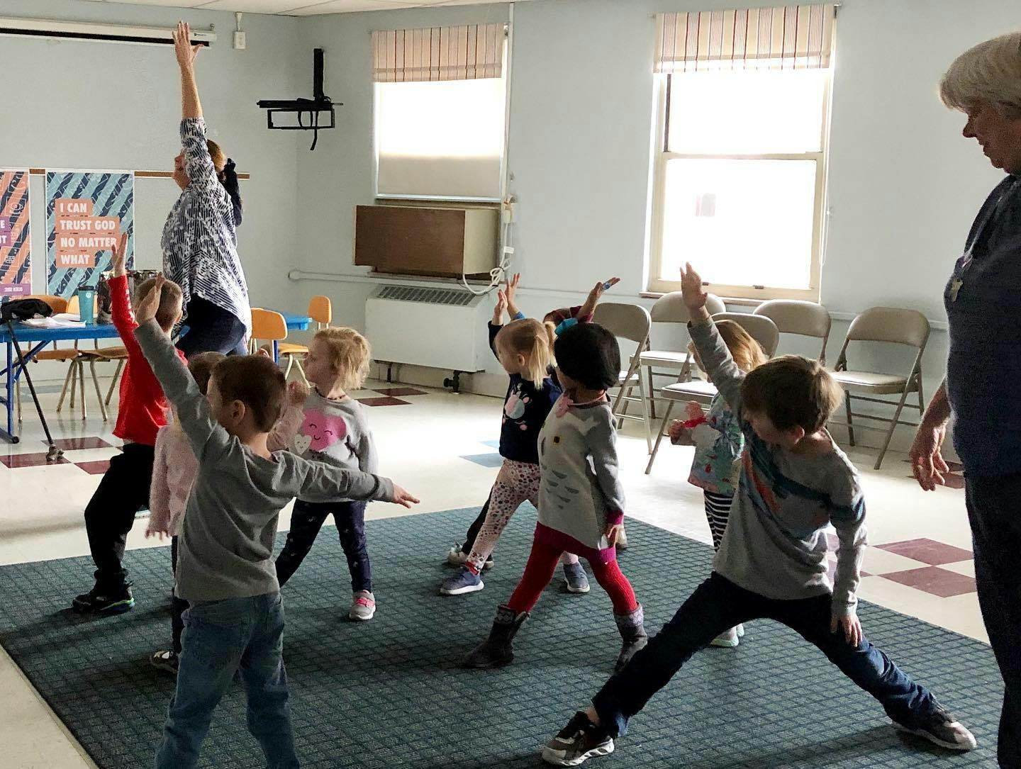 Adult and children doing yoga poses in a room