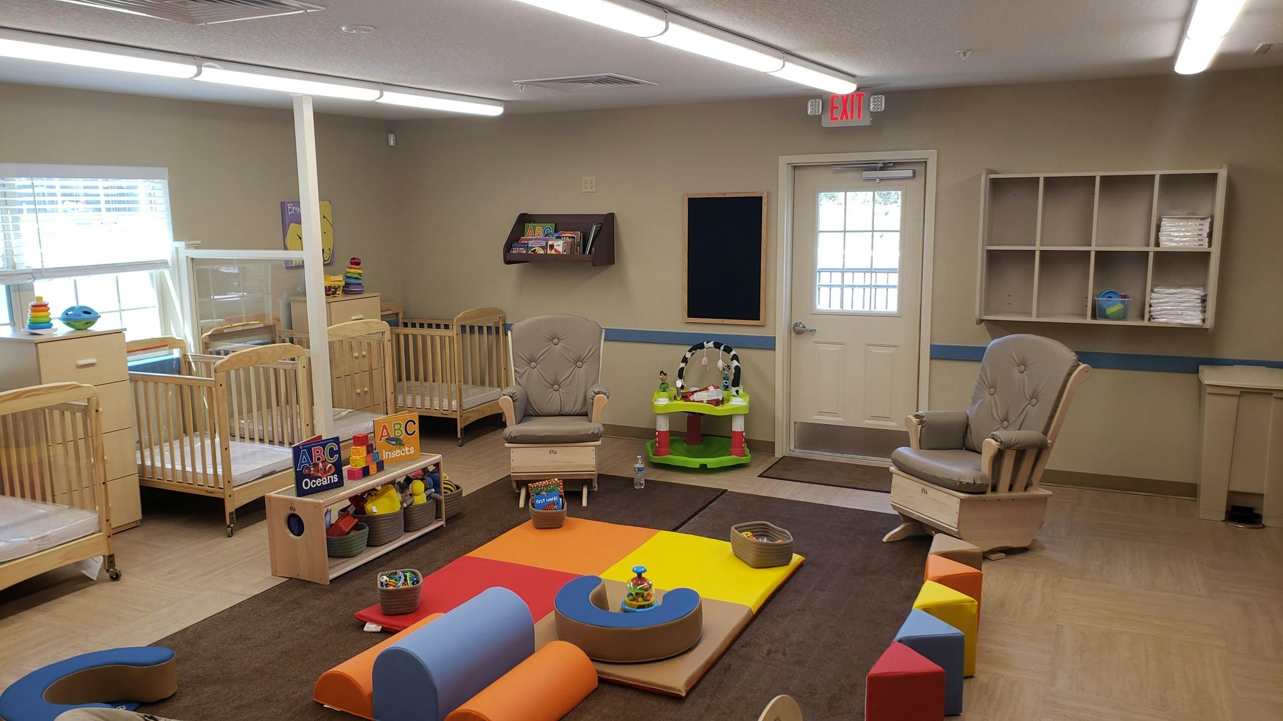 Nursery room with multiple cribs and a colorful play mat