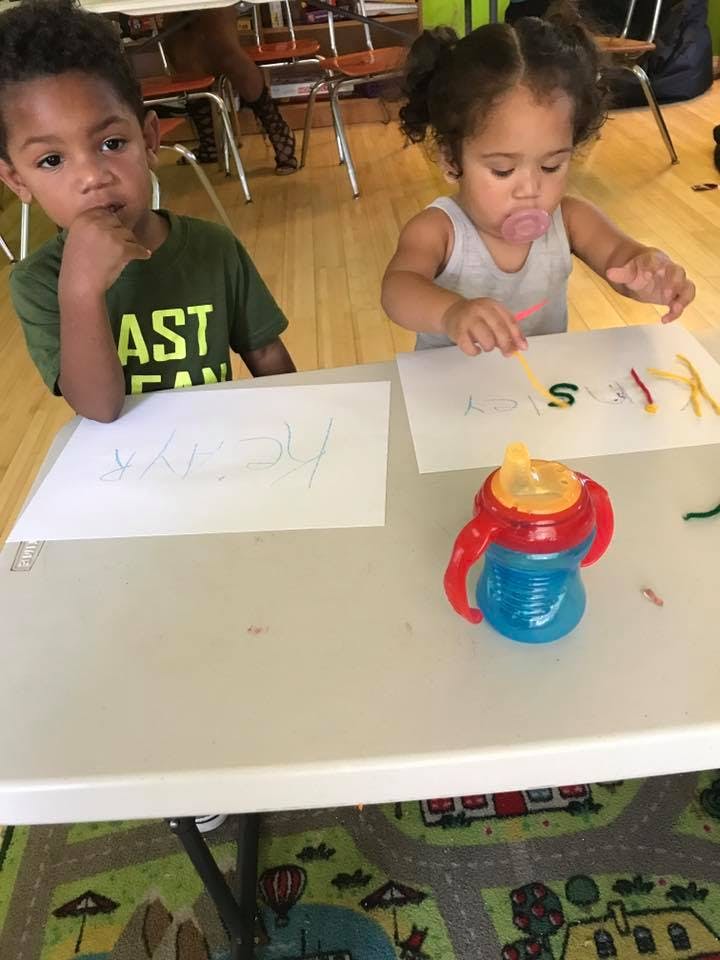 Two children at a table with paper and craft supplies
