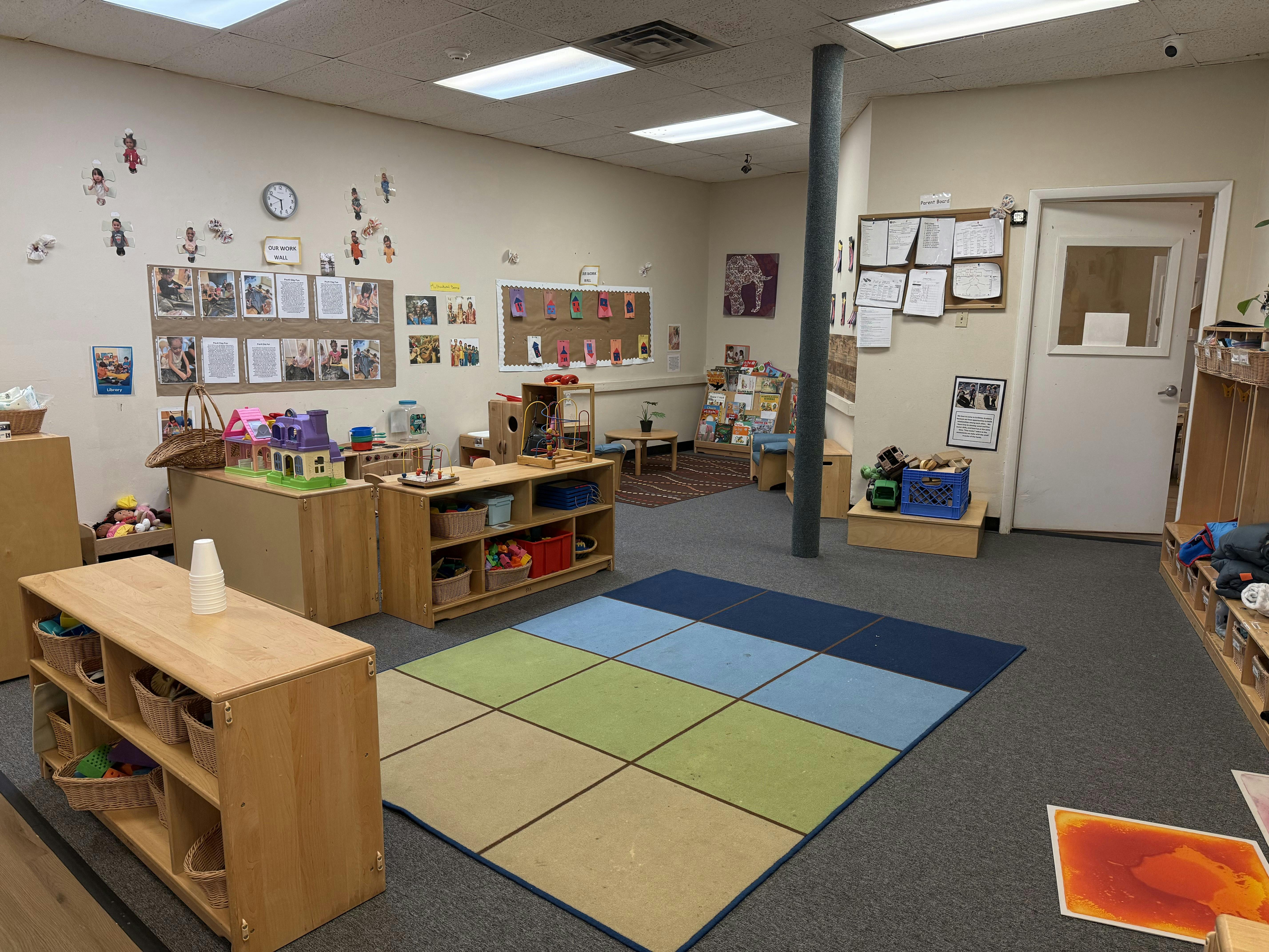 Classroom with colorful rug, wooden shelves, and bulletin boards