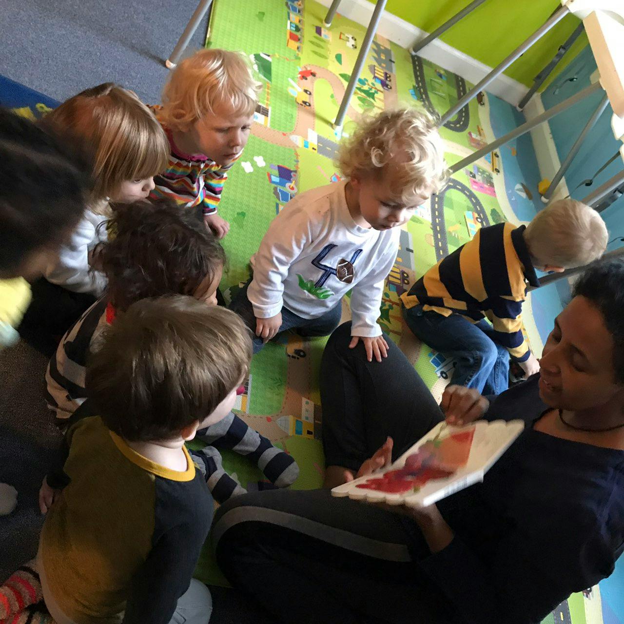 Person reading a book to a group of children