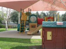 Playground with slides and climbing structures under a shade cover