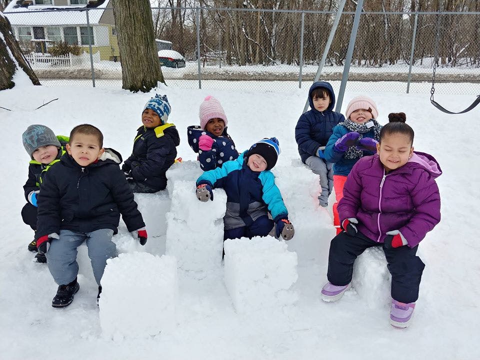Group of children sitting on snow blocks in a snowy outdoor area