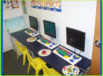 Three computer stations with colorful keyboards and yellow chairs