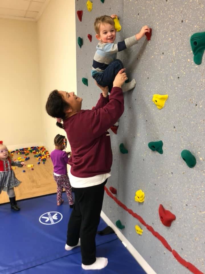 Person helping a child climb a rock wall